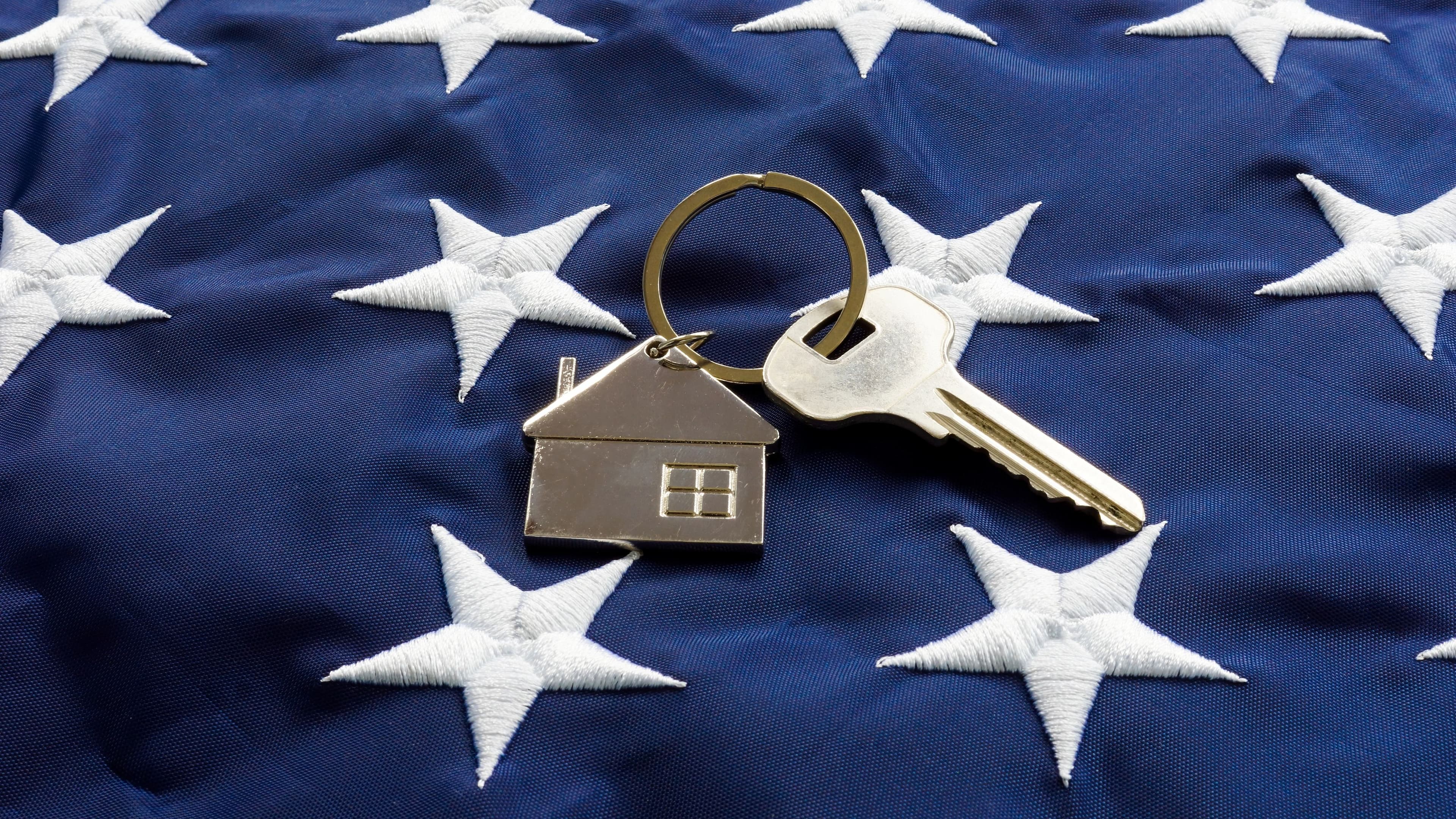 Still life of House-shaped key fob and key on a flag.