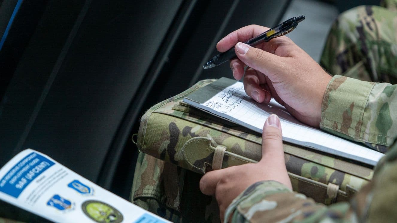 A close-up of two hands in uniform filling out a form.